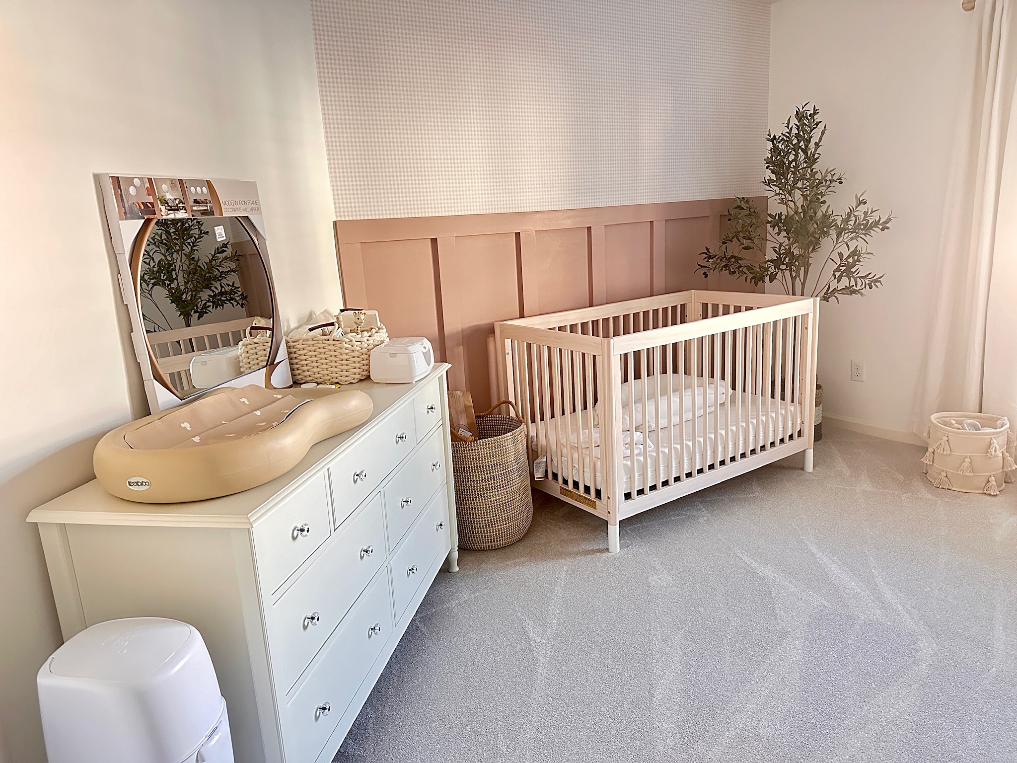 A modern nursery featuring a white crib, changing table, and decorative elements in a soft color palette.